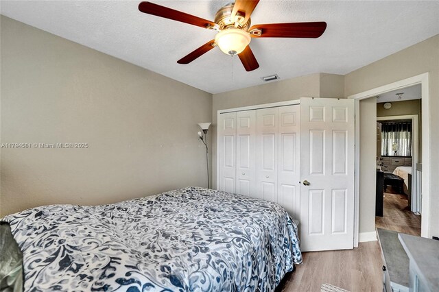 bedroom featuring visible vents, ceiling fan, wood finished floors, and a closet