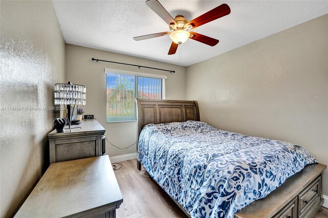 bedroom featuring a textured ceiling, baseboards, ceiling fan, and wood finished floors