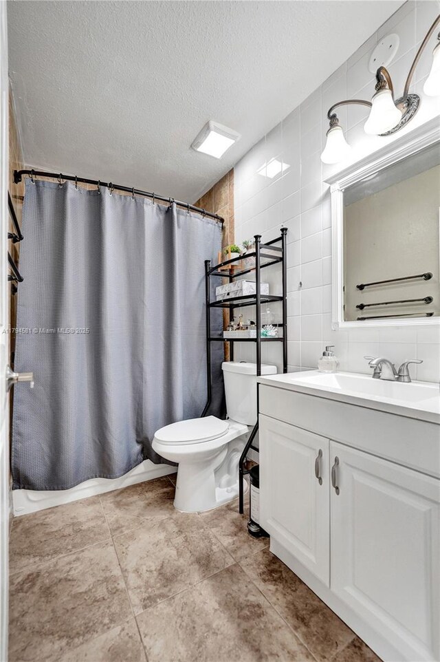 bathroom featuring a shower with curtain, a textured ceiling, tile walls, vanity, and toilet