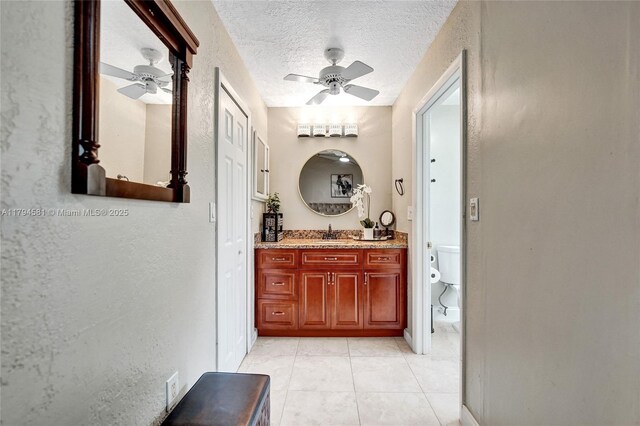 bathroom featuring tile patterned flooring, vanity, toilet, a textured ceiling, and a ceiling fan