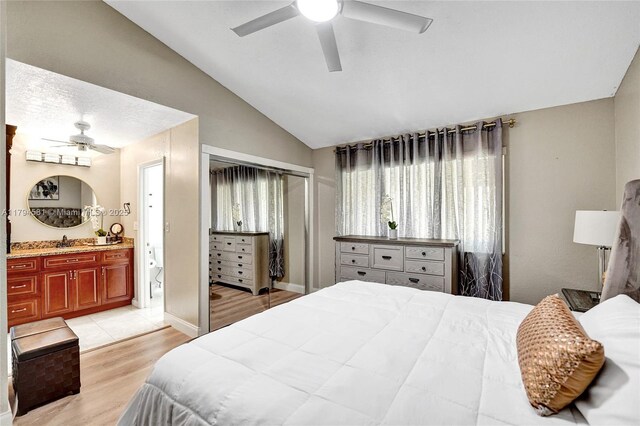 bedroom featuring a ceiling fan, light wood finished floors, connected bathroom, and lofted ceiling