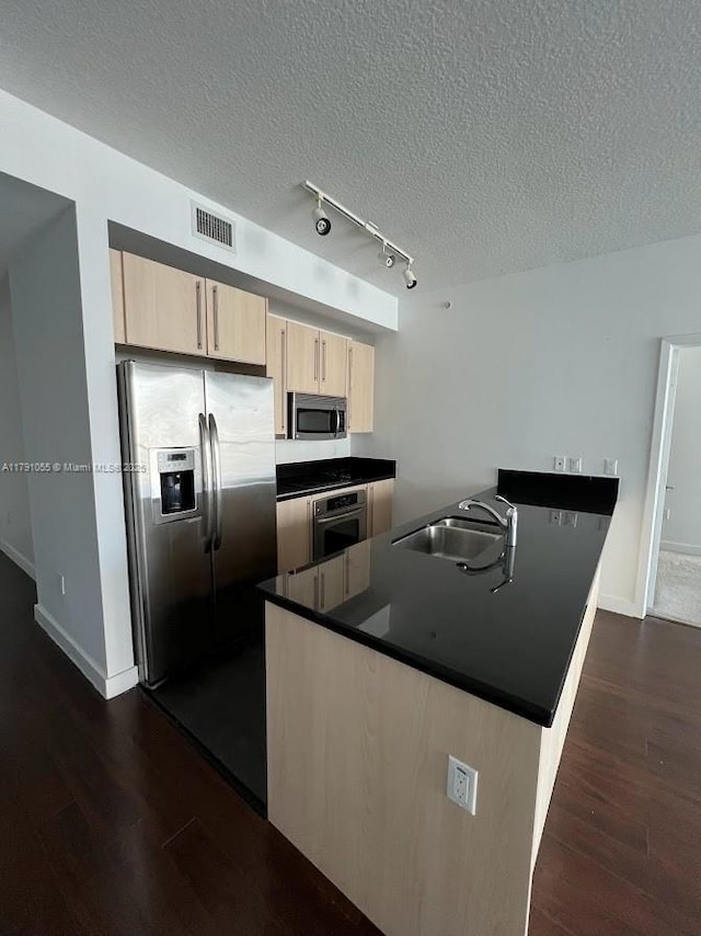 kitchen with dark wood-style flooring, a sink, light brown cabinets, stainless steel appliances, and visible vents