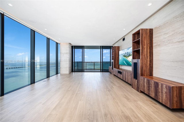 unfurnished living room with a wall of windows and light wood-type flooring