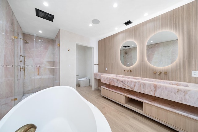 bathroom featuring visible vents, a freestanding tub, a stall shower, wood finished floors, and toilet