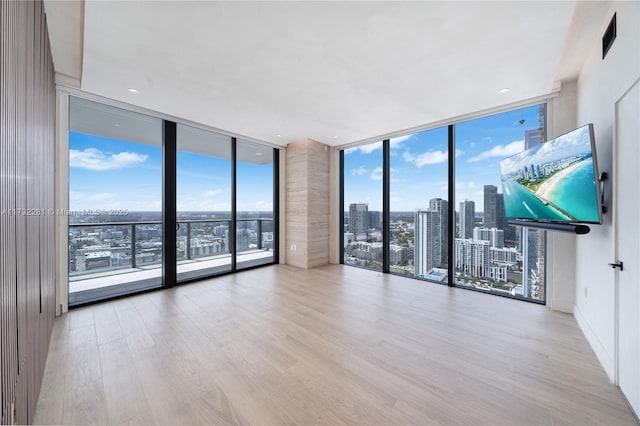 spare room with floor to ceiling windows and wood finished floors