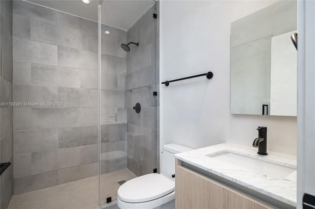 bathroom featuring vanity, a tile shower, and toilet