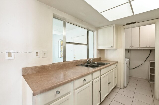 5810 NW 82nd Ter, Tamarac, FL 33321 - kitchen featuring a sink, washer and clothes dryer, white cabinetry, light tile patterned flooring, and light countertops