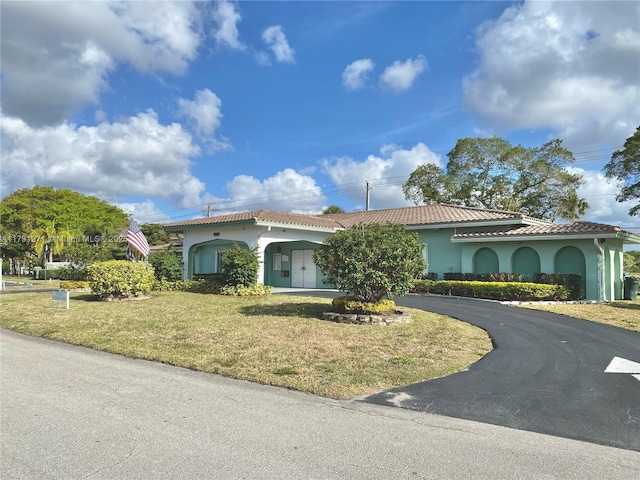 5810 NW 82nd Ter, Tamarac, FL 33321 - mediterranean / spanish house with stucco siding, a front yard, a tiled roof, and curved driveway