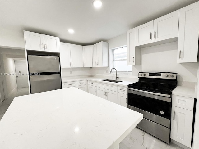 kitchen with marble finish floor, light countertops, white cabinetry, a sink, and appliances with stainless steel finishes