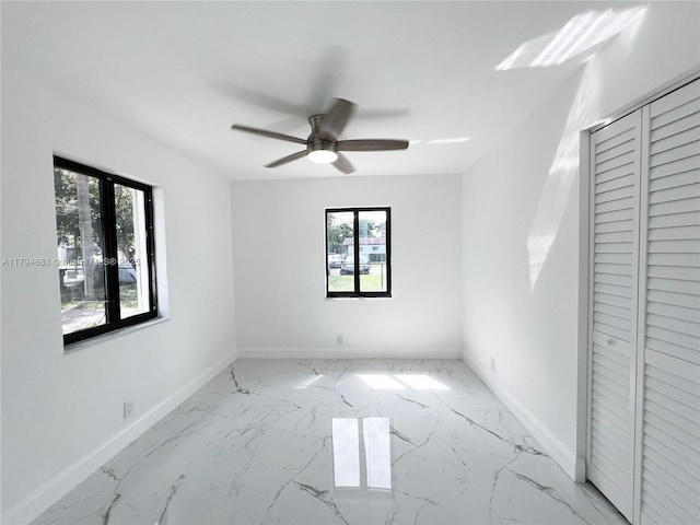 unfurnished bedroom featuring baseboards, multiple windows, ceiling fan, and marble finish floor