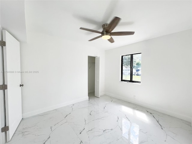unfurnished bedroom featuring baseboards, a ceiling fan, and marble finish floor