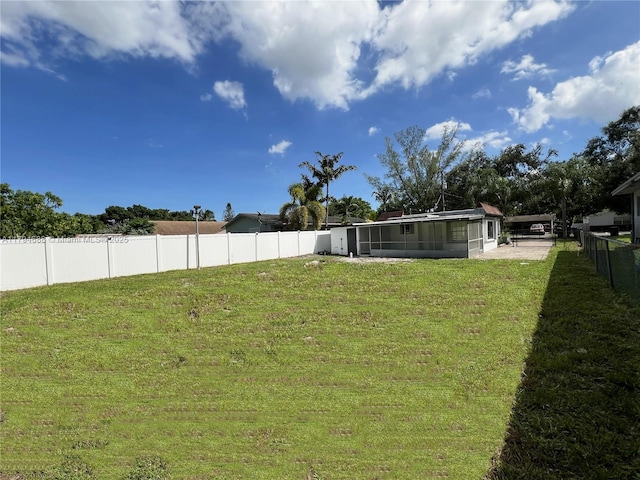 view of yard with a fenced backyard and a sunroom