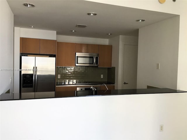 kitchen featuring backsplash, visible vents, appliances with stainless steel finishes, brown cabinets, and recessed lighting