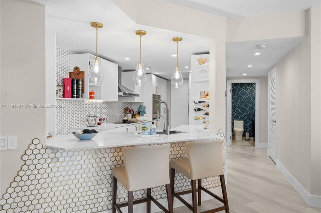 701 Brickell Key Blvd Unit 1812, Miami, FL 33131 - kitchen with a peninsula, wall chimney range hood, open shelves, light countertops, and white cabinets