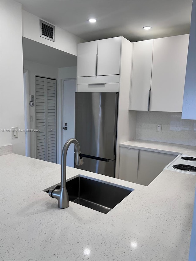 400 N Riverside Dr Unit 512, Pompano Beach, FL 33062 - kitchen featuring freestanding refrigerator, a sink, white cabinets, light stone countertops, and recessed lighting