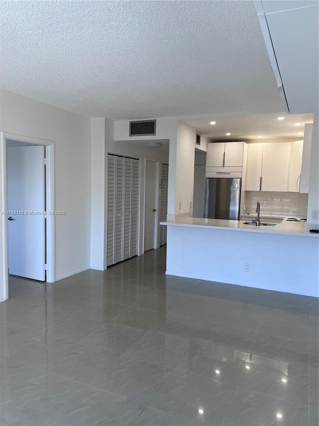 400 N Riverside Dr Unit 512, Pompano Beach, FL 33062 - kitchen with stainless steel fridge, a sink, light countertops, a peninsula, and white cabinets