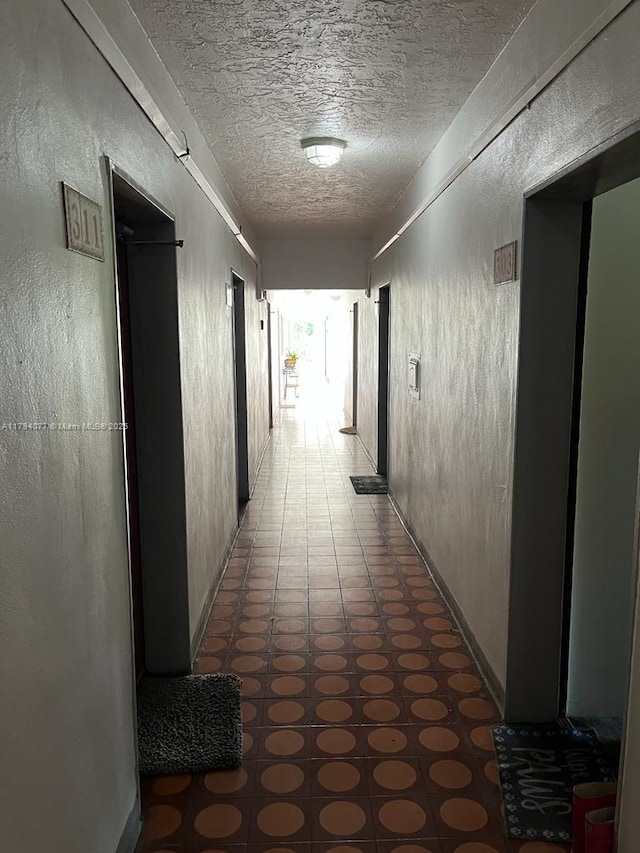 hall featuring tile patterned floors and a textured ceiling