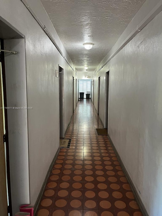 corridor featuring light floors and a textured ceiling