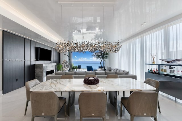 dining area featuring a high ceiling, a fireplace, and a notable chandelier