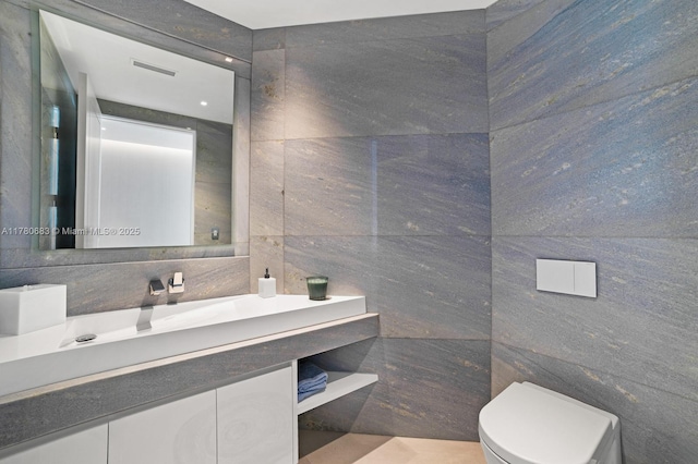 bathroom featuring tile walls, vanity, and toilet