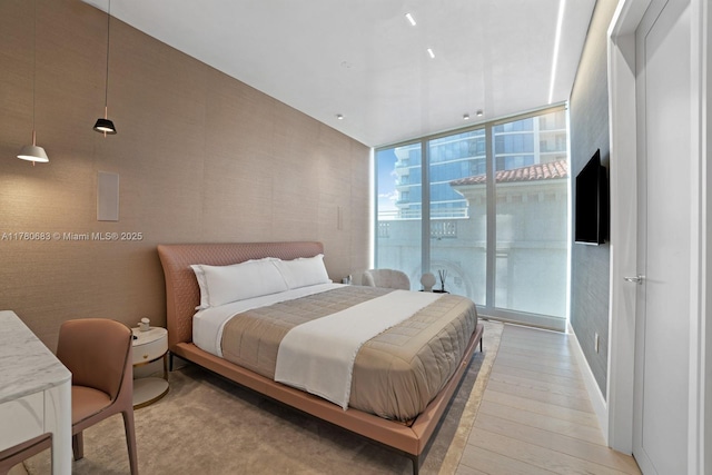 bedroom with a wall of windows and light wood-type flooring