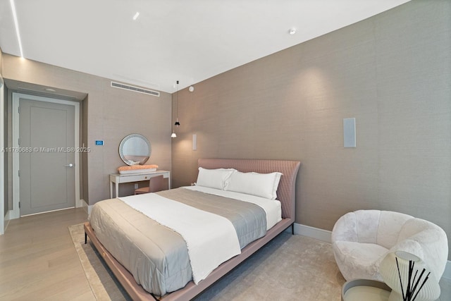 bedroom with baseboards, light wood finished floors, and visible vents