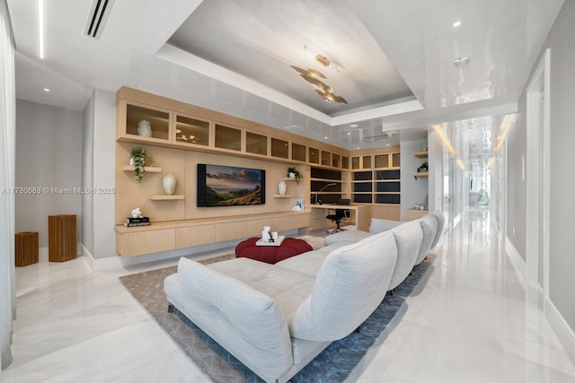 living room with a tray ceiling, built in shelves, and visible vents