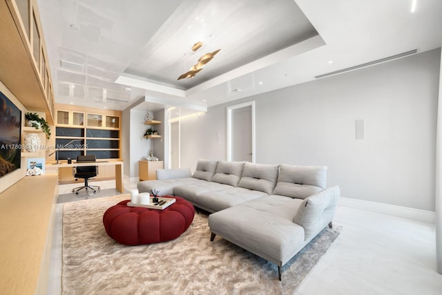living area featuring baseboards, built in features, a raised ceiling, and built in study area