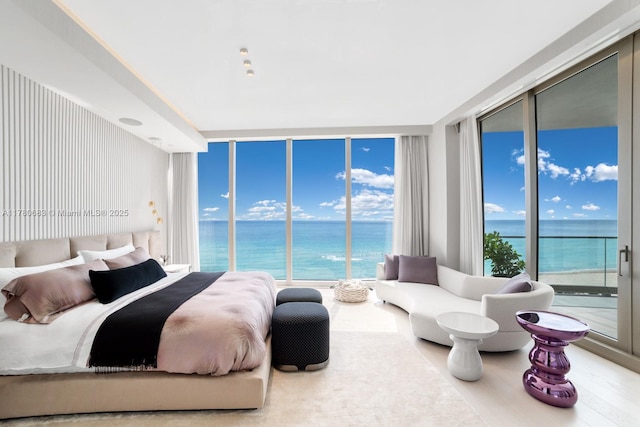 bedroom with a water view, expansive windows, and access to exterior