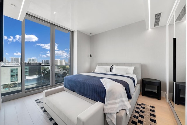bedroom with a city view, wood finished floors, and visible vents