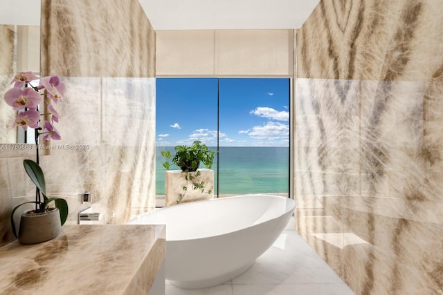 bathroom with tile walls, a soaking tub, and a water view