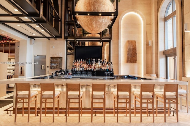 bar featuring a wealth of natural light, a bar, and a towering ceiling