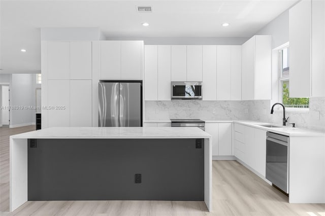 4629 Mariners Cove Dr, Wellington, FL 33449 - kitchen with appliances with stainless steel finishes, a kitchen island, backsplash, white cabinetry, and recessed lighting