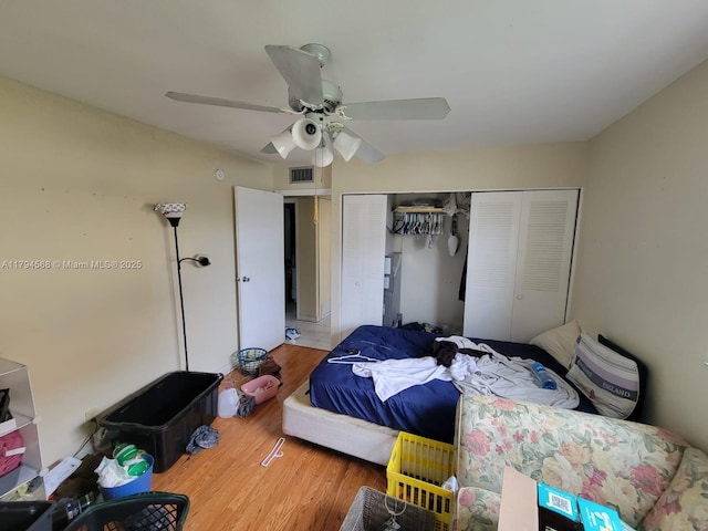 bedroom with ceiling fan, a closet, wood finished floors, and visible vents