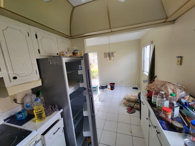 kitchen featuring stove, light tile patterned floors, light countertops, white cabinets, and a chandelier
