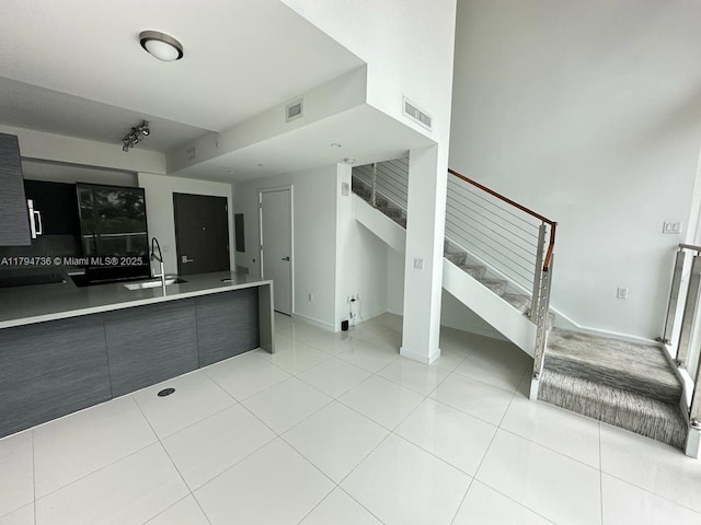 unfurnished living room featuring visible vents, a sink, stairs, and light tile patterned flooring