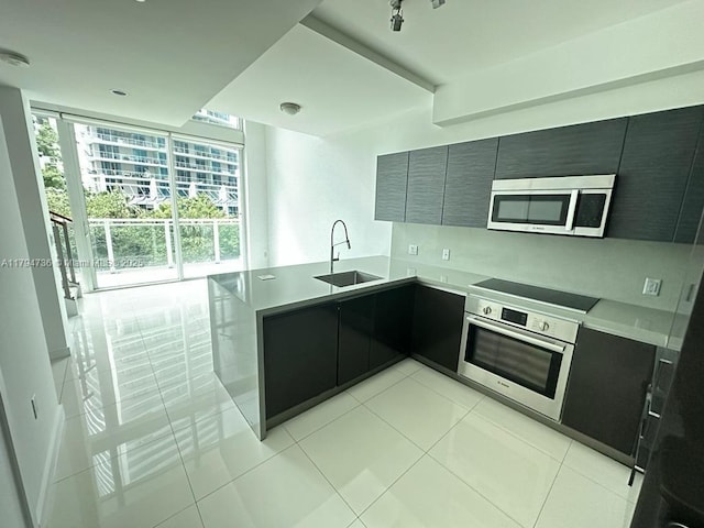 kitchen with a sink, light countertops, stainless steel appliances, a peninsula, and modern cabinets