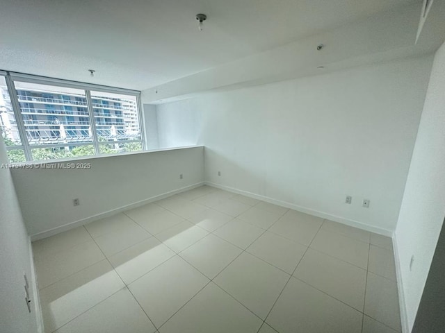 spare room with baseboards and tile patterned floors