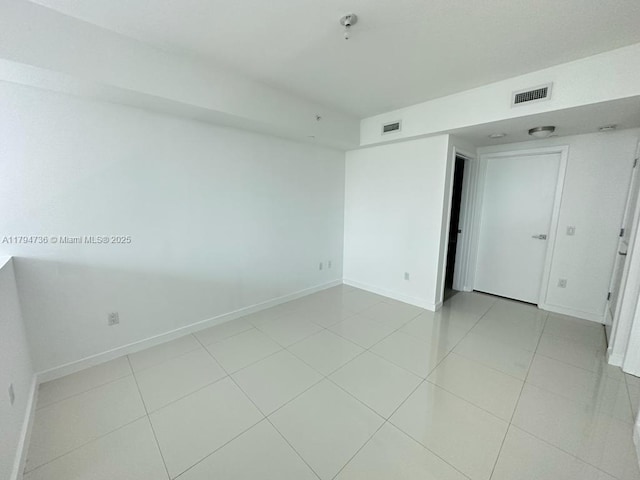 spare room featuring light tile patterned floors, baseboards, and visible vents