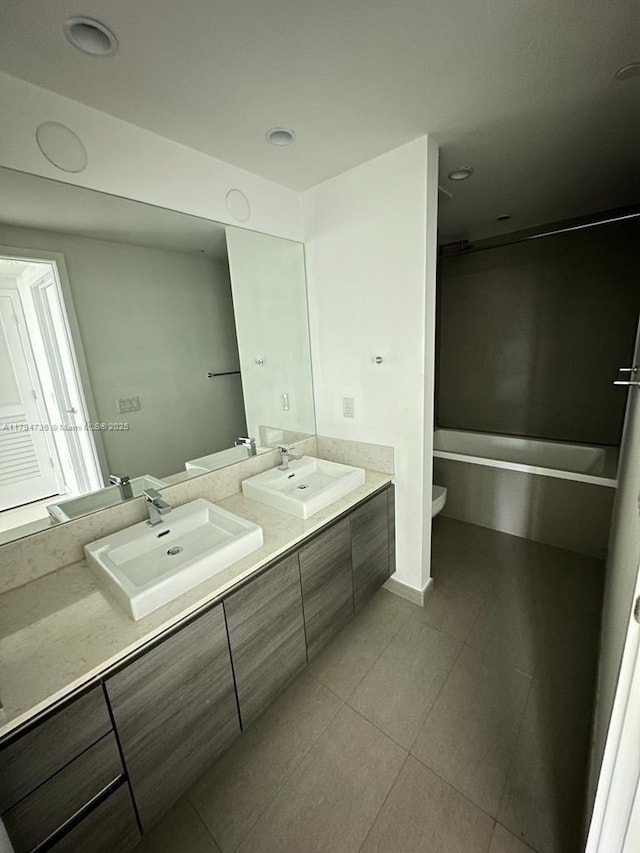 bathroom featuring double vanity, a sink, tile patterned floors, and toilet