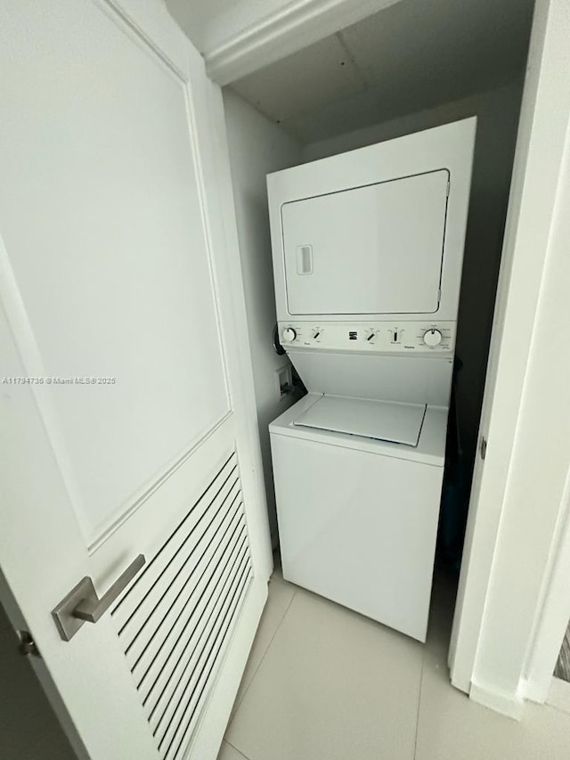 laundry room with laundry area, stacked washer / drying machine, and light tile patterned flooring