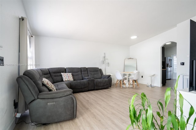 living area with arched walkways, baseboards, recessed lighting, and light wood finished floors