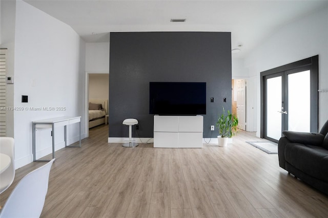 living area with visible vents, light wood-style floors, baseboards, and french doors