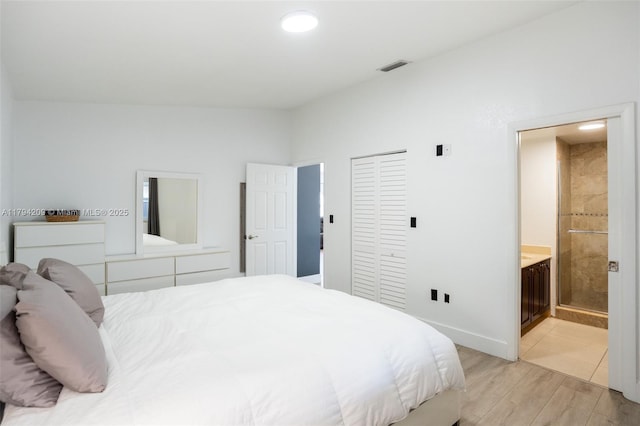 bedroom featuring ensuite bath, baseboards, light wood-type flooring, visible vents, and a closet