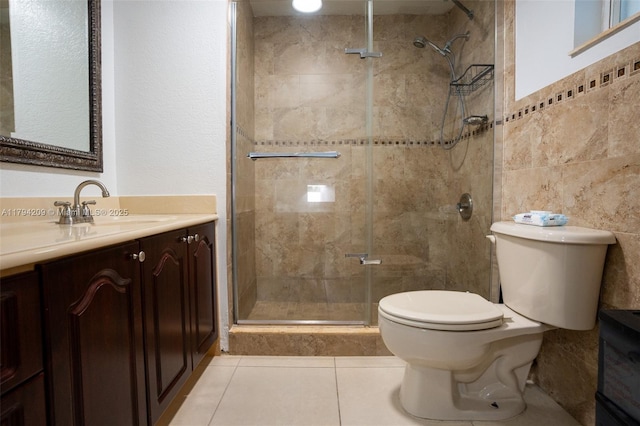 bathroom featuring tile patterned flooring, vanity, toilet, tile walls, and a stall shower