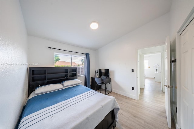 bedroom featuring baseboards, lofted ceiling, and light wood-type flooring