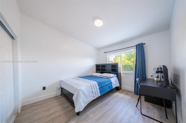 bedroom featuring baseboards, lofted ceiling, and light wood-type flooring