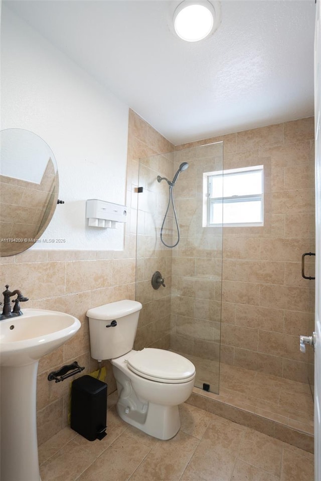full bathroom with tile patterned floors, a stall shower, toilet, and tile walls