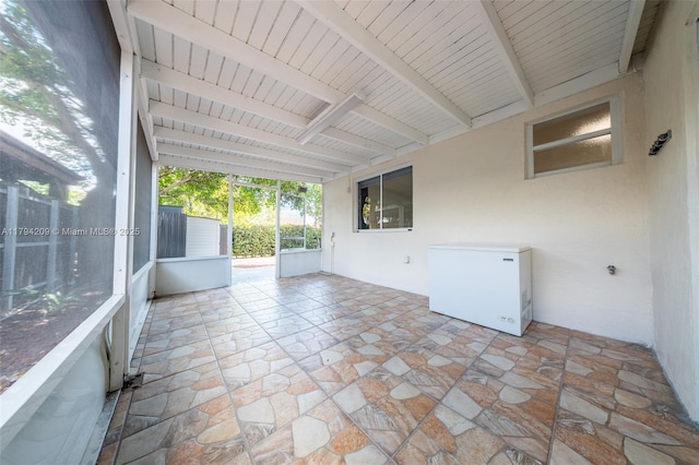 unfurnished sunroom with beam ceiling