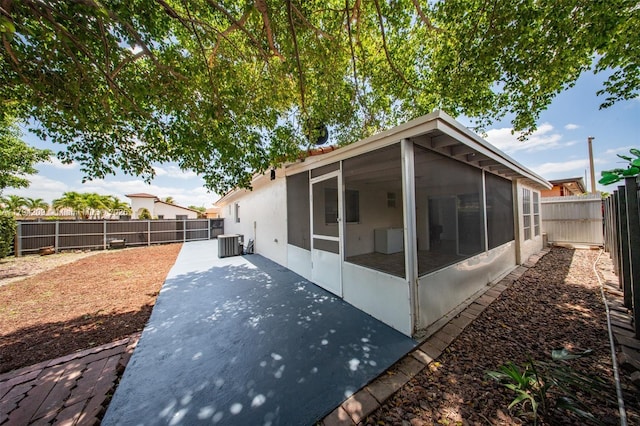 back of house featuring central AC, a patio, a fenced backyard, stucco siding, and a sunroom